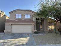 Two-story home featuring a two-car garage, desert landscaping, and a tree in the front yard at 12733 W Boca Raton Rd, El Mirage, AZ 85335