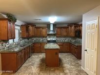 Spacious kitchen with dark wood cabinets, a center island, and stainless steel appliances at 12733 W Boca Raton Rd, El Mirage, AZ 85335