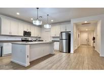Bright, white kitchen featuring stainless steel appliances, a center island, and wood-look tile flooring at 559 W Magena Dr, San Tan Valley, AZ 85140
