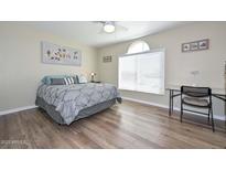 This spacious bedroom features wood floors, a ceiling fan, and a large window at 8444 W Rockwood Dr, Peoria, AZ 85382