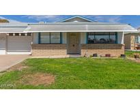 Traditional home with a well-maintained lawn and brick accents creating a warm and inviting curb appeal at 10417 N 95Th Dr # B, Peoria, AZ 85345
