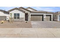 Charming single-story home featuring stone accents, a three-car garage, and desert landscaping at 17742 W Brown St, Waddell, AZ 85355