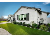 Charming home exterior with manicured lawn, decorative trellis, and inviting curb appeal in a sunny setting at 17801 W Mountainair St, Surprise, AZ 85388