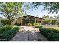 Modern home featuring a sleek glass facade, inviting entryway, and lush, manicured landscaping enhancing curb appeal at 6301 E Exeter Blvd, Scottsdale, AZ 85251