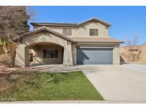 Inviting two-story home featuring a covered carport, a well-maintained lawn, and a neutral-toned facade at 15934 W Banff Ln, Surprise, AZ 85379