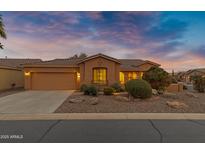 Inviting single-story home featuring a two-car garage, desert landscaping, and neutral color palette under a vibrant evening sky at 42975 W Misty Morning Ln, Maricopa, AZ 85138