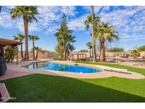 Backyard pool featuring a diving board, lush turf and mature palm trees under a sunny sky at 6208 W Willow Ave, Glendale, AZ 85304