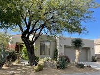 Charming desert home featuring barrel cactus, desert landscaping, and an attached two-car garage at 7016 E Stone Raven Trl, Scottsdale, AZ 85266