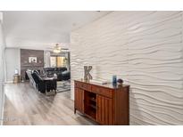 Inviting living room with modern accent wall and wood-look flooring flows into comfortable seating area at 8231 N 21St Dr # E101, Phoenix, AZ 85021