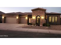 Charming home featuring stone accents, an arched entry, two-car garage, and well-maintained landscaping at 8928 E Wethersfield Rd, Scottsdale, AZ 85260