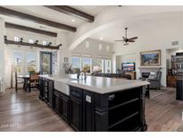 Expansive kitchen island with black cabinetry, farm sink, and seating, open to living room with beamed ceilings at 9565 E Mountain Spring Rd, Scottsdale, AZ 85255