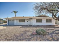 Charming single-story home with a desert landscaped front yard, a palm tree, and a two-car garage at 12021 N Riviera Ct, Sun City, AZ 85351