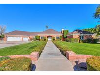 Charming single-story home with a beautiful red brick facade, manicured lawn, and a three-car garage at 1520 E Elmwood Cir, Mesa, AZ 85203