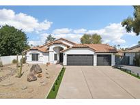 Charming single-story home with a desert landscape, barrel tile roof, and three-car garage at 5704 E Estrid Ave, Scottsdale, AZ 85254