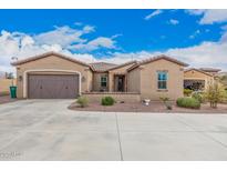 Charming single-story home with a two-car garage, landscaped front yard, and a tile roof under a blue sky at 41553 W Springtime Rd, Maricopa, AZ 85138
