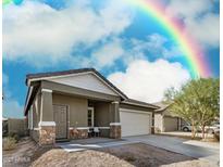 Charming single-story home with a two-car garage, stone accents, and a rainbow in the sky at 6513 W Latona Rd, Laveen, AZ 85339