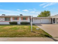 Charming single-story home with a well-maintained front yard, covered garages, and light blue skies at 10408 N 105Th Ave, Sun City, AZ 85351