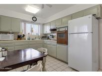 Traditional kitchen featuring gray cabinets, tile countertops, white appliances, and an adjacent dining area at 10408 N 105Th Ave, Sun City, AZ 85351