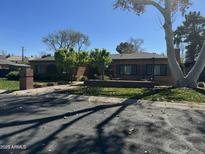 Charming brick home featuring a well-manicured front yard and mature trees, creating a welcoming curb appeal at 115 W Rose Ln, Phoenix, AZ 85013