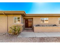 Charming front entrance with custom wooden door, brick accent wall, and desert landscaping at 25261 S Berry Brook Dr, Sun Lakes, AZ 85248