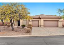 Tan home featuring a three-car garage, desert landscaping, and mature mesquite tree at 3138 W Ravina Ln, Anthem, AZ 85086