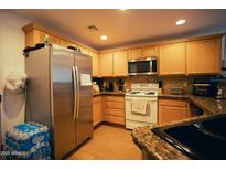 Well-lit kitchen featuring wooden cabinets, granite countertops, and stainless steel appliances, designed for culinary enthusiasts at 3150 E Beardsley Rd # 1105, Phoenix, AZ 85050