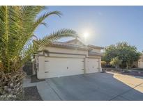 View of the home's large three car garage, desert landscaping and stucco exterior, which are well maintained at 2621 S 157Th Dr, Goodyear, AZ 85338