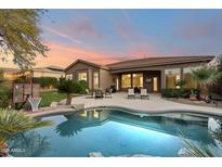 Relaxing backyard with a sparkling pool, covered patio, and lush landscaping; perfect for entertaining or unwinding at 5892 E Evening Glow Dr, Scottsdale, AZ 85266