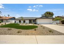 Charming single-story home featuring a well-manicured front yard, complemented by neutral color palette and large garage at 7624 E Charter Oak Rd, Scottsdale, AZ 85260