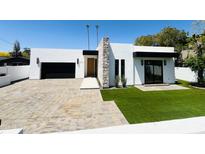 Modern home featuring a stone accent wall, desert landscaping, and spacious paver driveway at 3106 N Valencia Ln, Phoenix, AZ 85018