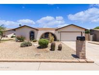 Tan single story home featuring a xeriscaped front yard, archway entry and two car garage at 4828 E Capistrano Ave, Phoenix, AZ 85044