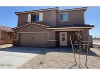 Two-story home featuring a two-car garage, a covered porch, and low-maintenance gravel landscaping at 1057 W West Virginia Ave, Florence, AZ 85132