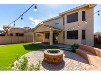 Lush backyard features artificial grass, patio, outdoor lighting, and brick firepit at 390 W Wisteria Pl, Chandler, AZ 85248