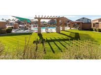 Beautiful community pool and lounging area with green grass and shade structures at 1350 S Greenfield Rd # 1016, Mesa, AZ 85206