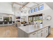 Open-concept space with wood floors and chef's kitchen, flowing into the living room at 19494 N 98Th Pl, Scottsdale, AZ 85255