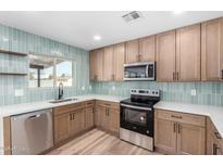 Bright kitchen features modern appliances, beautiful cabinetry, stylish backsplash and light wood flooring at 2908 E Escondido Ave, Mesa, AZ 85204