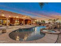 Backyard pool and spa with rock waterfall feature against desert sunset at 29423 N 145Th Pl, Scottsdale, AZ 85262