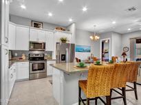 Modern kitchen featuring white cabinets, stainless steel appliances, an island with bar stools and granite countertops at 4241 N Pebble Creek Pkwy # 42, Goodyear, AZ 85395