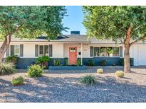 Charming home featuring xeriscape landscaping, mature shade trees, and a vibrant coral colored front door at 3326 N 82Nd Pl, Scottsdale, AZ 85251