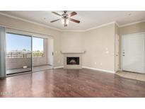 Bright living room features a fireplace, ceiling fan, and sliding glass doors to the balcony at 5345 E Van Buren St # 308, Phoenix, AZ 85008