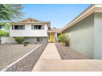 Charming two-story home featuring a bright yellow front door and low-maintenance desert landscaping at 8338 E Stella Ln, Scottsdale, AZ 85250