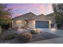 Inviting single-story home featuring neutral stucco, a two-car garage, desert landscaping, and an American flag at 2009 E Lindrick Dr, Gilbert, AZ 85298