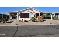 Charming home featuring an American flag, mature landscaping, and a covered carport for convenient parking at 2400 E Baseline Ave # 58, Apache Junction, AZ 85119