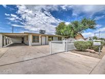 Charming single-story home with a white fence, lush landscaping, and a covered carport at 416 W Chambers St, Phoenix, AZ 85041