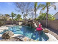 Backyard pool features a rock waterfall, slide, and clear blue water, perfect for relaxation at 1113 E Devon Dr, Gilbert, AZ 85296