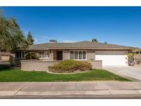 Charming single-story brick home with a manicured lawn and a spacious two-car garage on a sunny day at 1506 E Gemini Dr, Tempe, AZ 85283