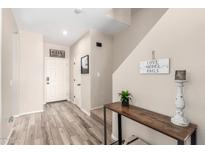 Inviting entryway featuring wood-look tile flooring, a decorative table, and a charming welcome sign at 17445 N 185Th Dr, Surprise, AZ 85374