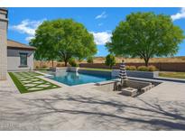 Stunning backyard pool with lush landscaping, a fire pit, and a lounging area for relaxation and outdoor enjoyment at 20125 E Melissa Pl, Queen Creek, AZ 85142