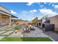 Spacious backyard features a cozy outdoor seating area and a stylish built-in fireplace at 20981 E Watford Dr, Queen Creek, AZ 85142