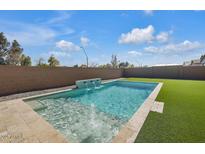 Beautiful pool with integrated spa and water feature in a fenced backyard with artificial turf at 21757 S 191St Pl, Queen Creek, AZ 85142